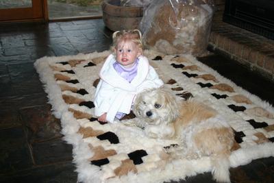 Granddaughter Codie, sitting on an alpaca rug with our dog Yoshi
